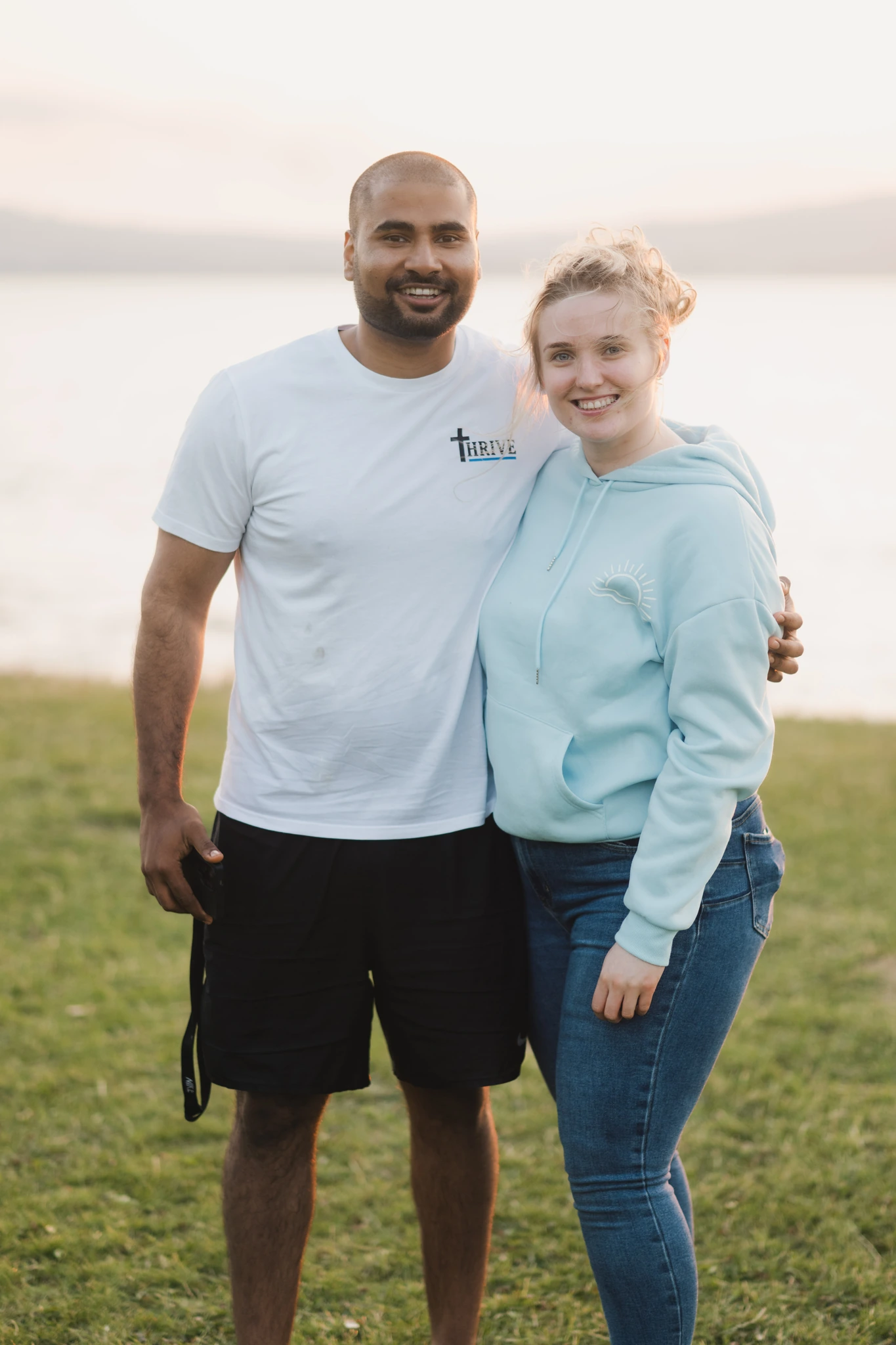 a man and woman posing in front of a lake