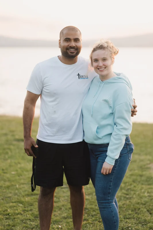 a man and woman posing in front of a lake