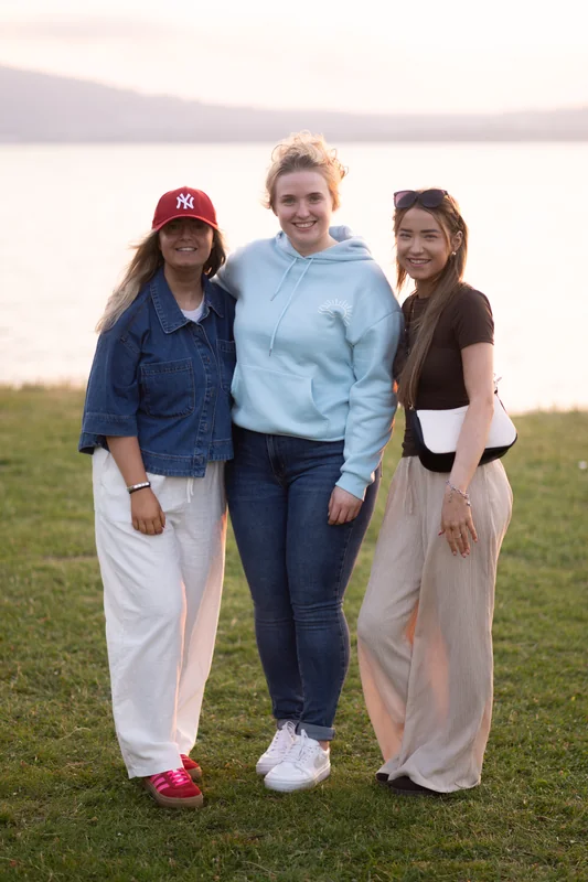 three women standing in front of a lake