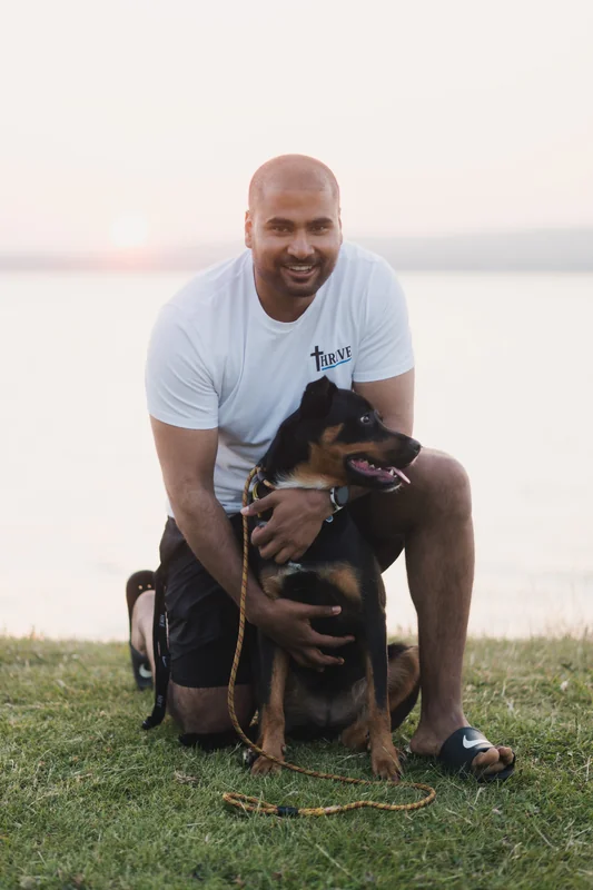 a man with a dog on his lap in front of a lake