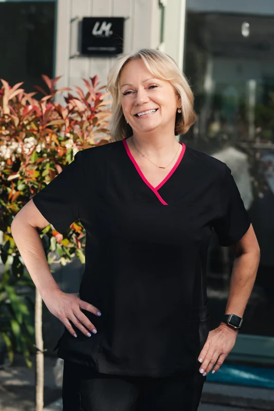 a woman in black scrubs standing in front of a building