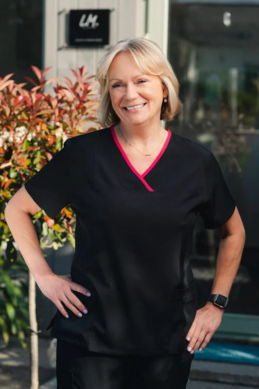 a woman in black scrubs standing in front of a doorway