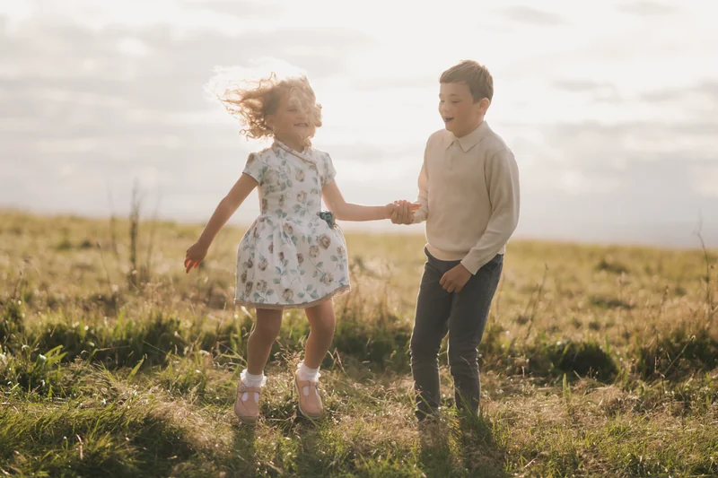 a girl and boy play in a grassy field