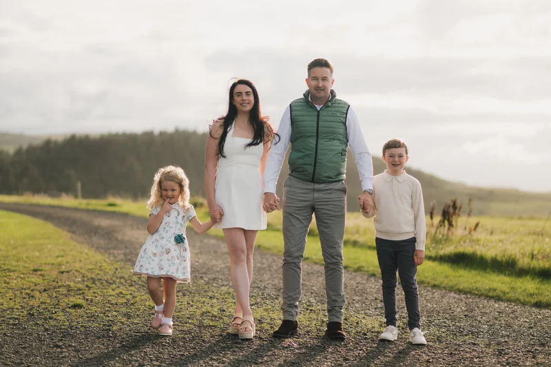 a couple and their children are standing on a path in a field