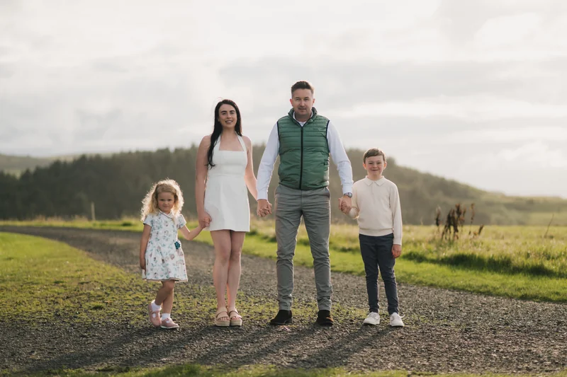 a couple and their children stand on a path in a field