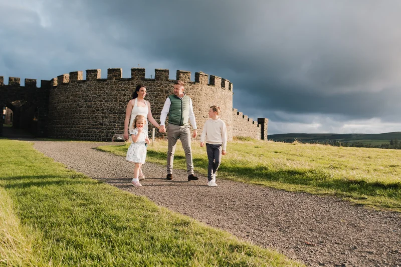 a family walking down a path with a castle in the background