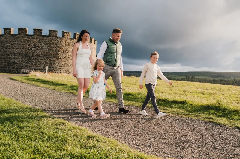 a family walking down a path with a castle in the background