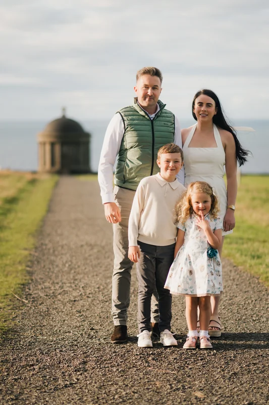 a family poses with their children on a path in front of a castle
