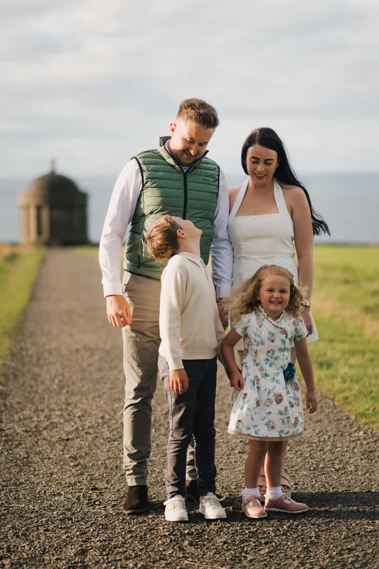 a family poses with their children on a path in front of a castle