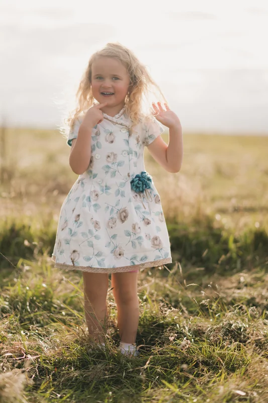 a little girl in a blue and white floral dress