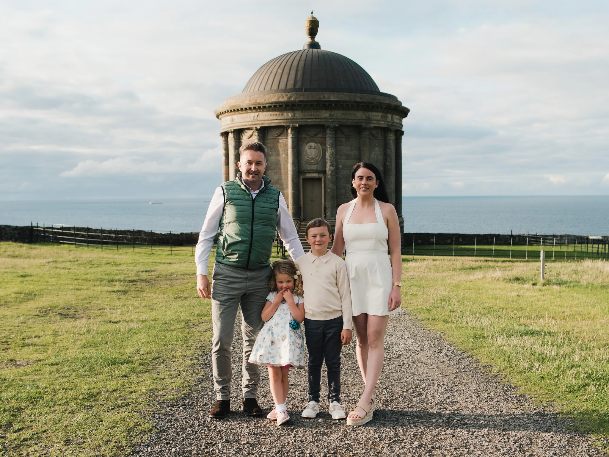 a family poses in front of a building with a tree in the background