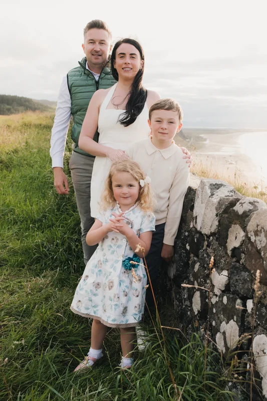 a couple poses with their children in front of a stone wall