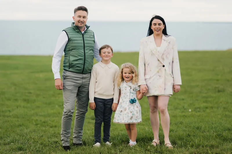 a family standing in a field with their children in front of them