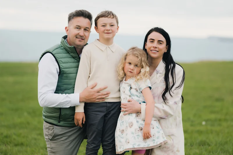 a man and a woman pose with their children in a field