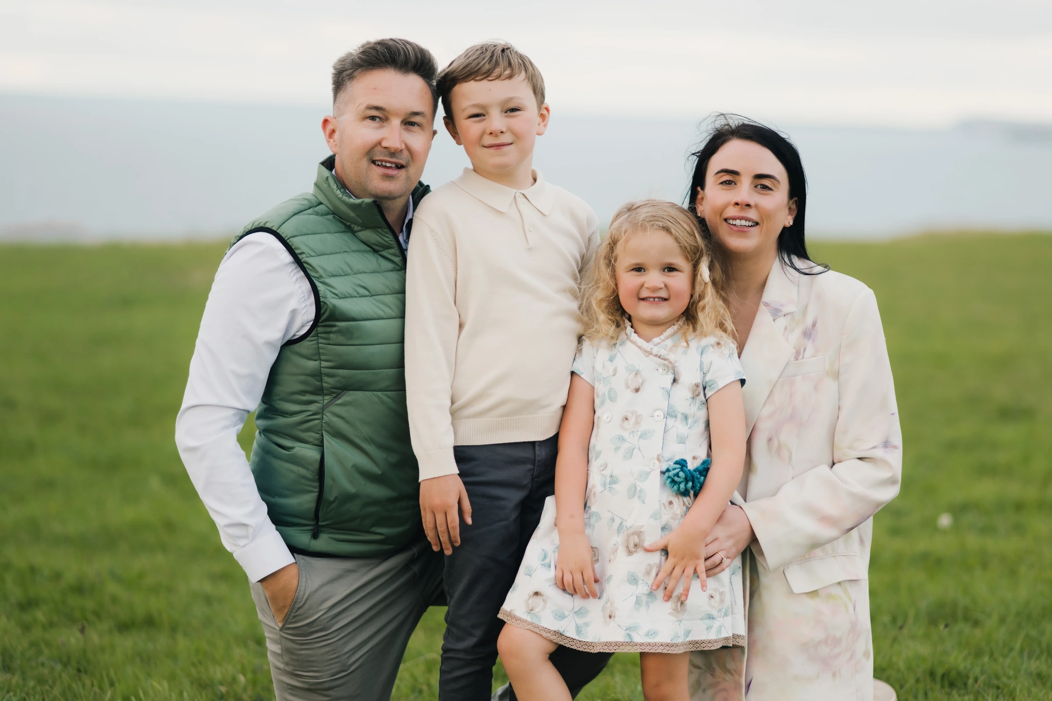 a man and woman pose for a family photo in a field with their children