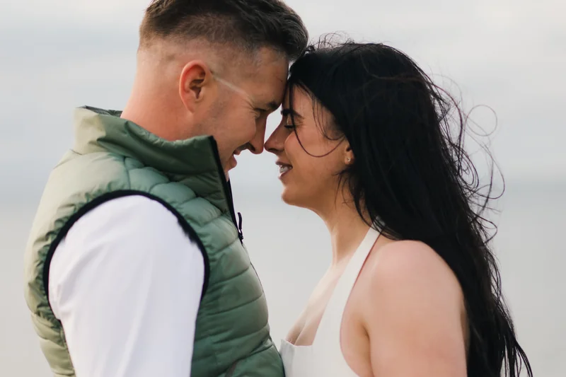 a bride and groom kiss on the beach during their engagement session
