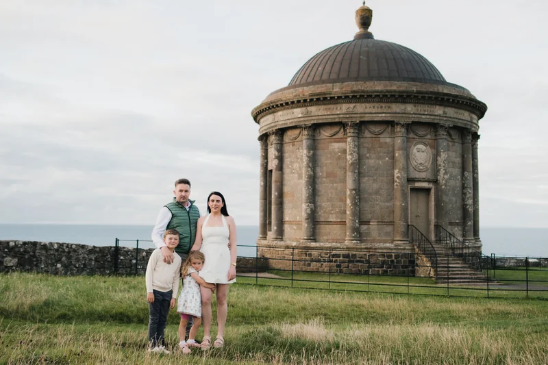 a family poses in front of a large stone building