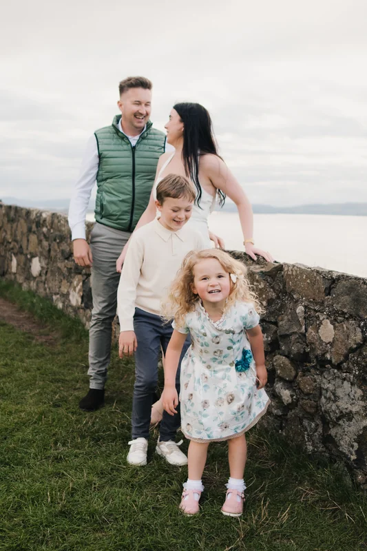 a family portrait of a couple and their children posing in front of the sea