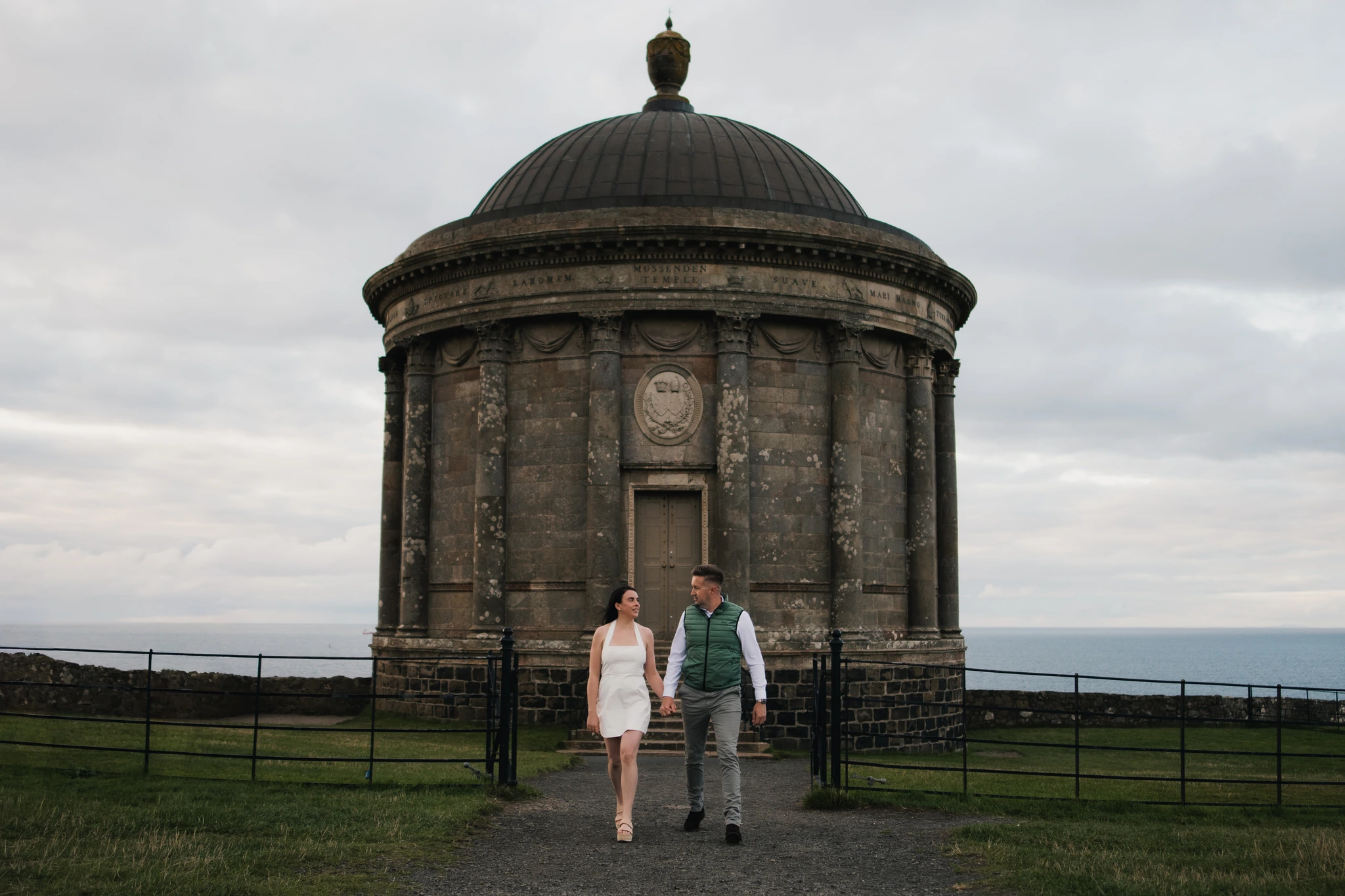 a bride and groom are walking down a path towards a large stone building
