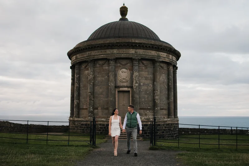 a bride and groom are walking down a path towards a large stone building