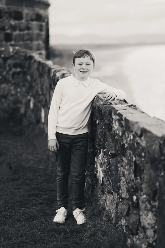 a boy leans against a wall in front of a castle