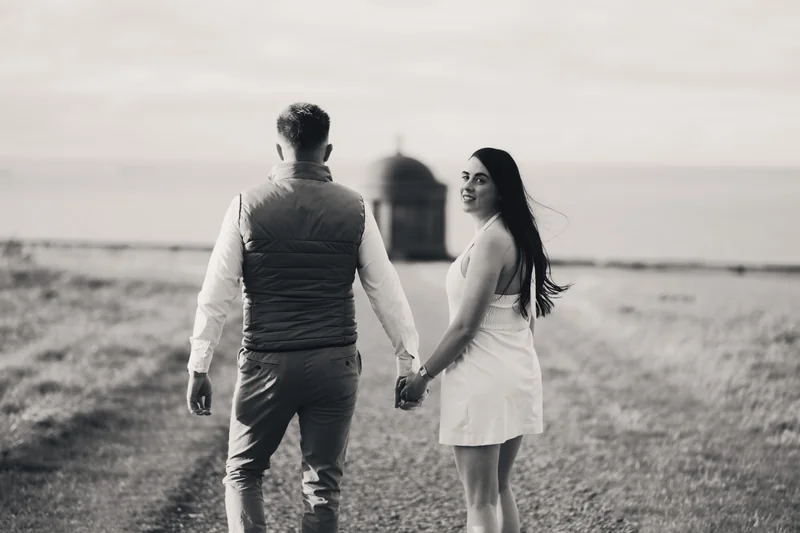 a man and woman walk down a path in front of a castle