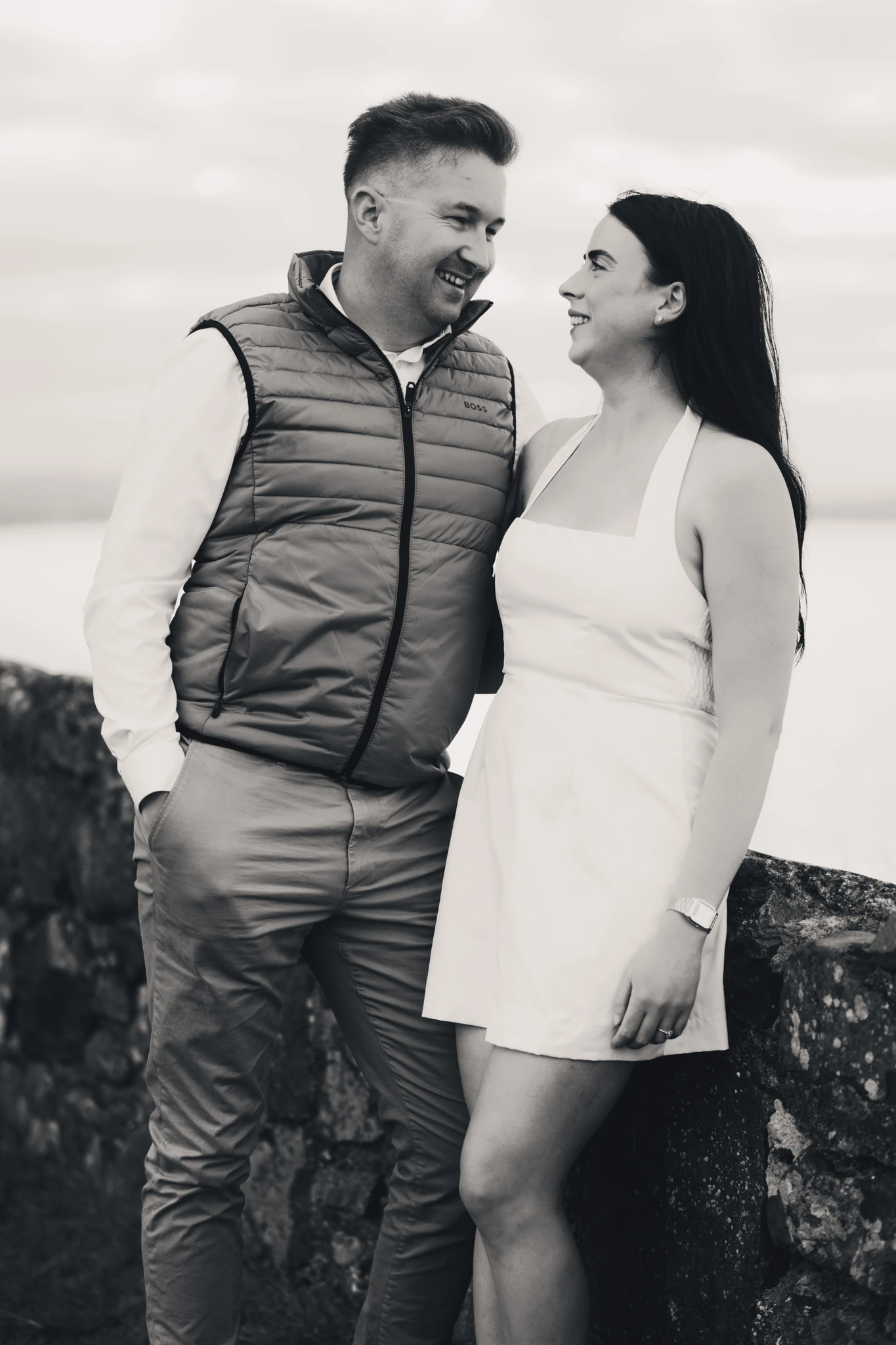 a man and woman are standing on a stone wall in front of a black and white photograph