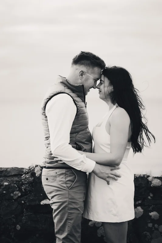 a bride and groom kissing in front of a stone wall