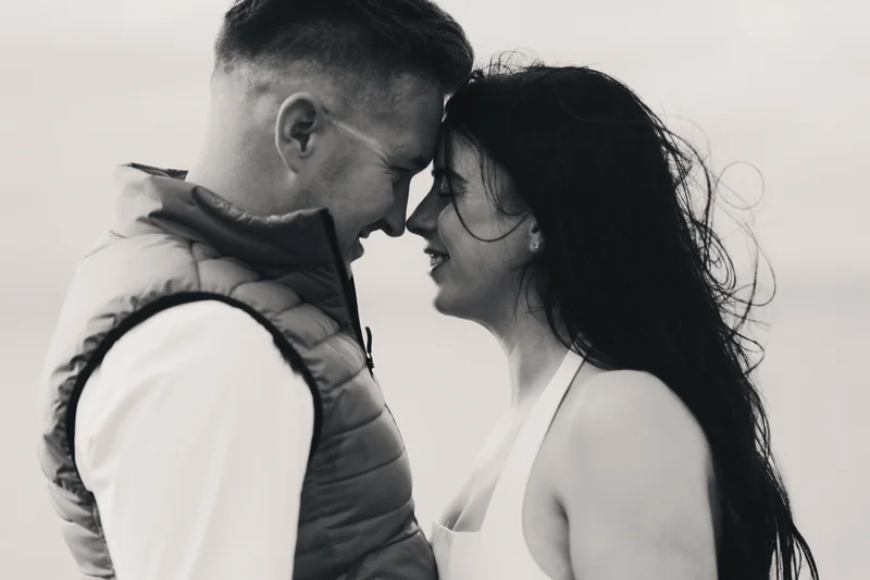 a man and woman hugging in front of a black and white photograph