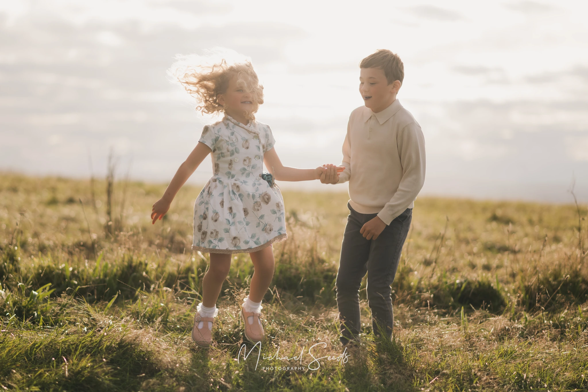 a girl and boy play in a grassy field