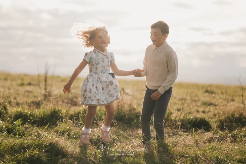 a girl and boy play in a grassy field