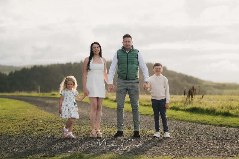 a couple and their children are standing on a path in a field