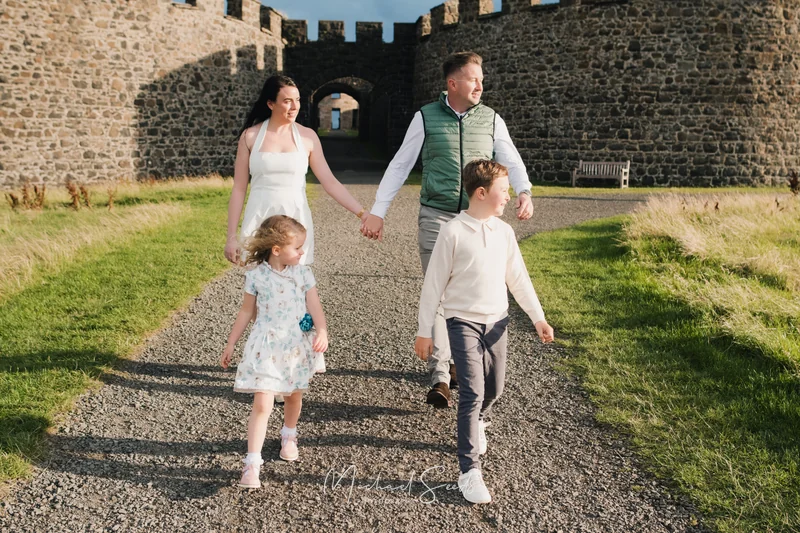 a couple and their children walk down a stone path in front of a castle
