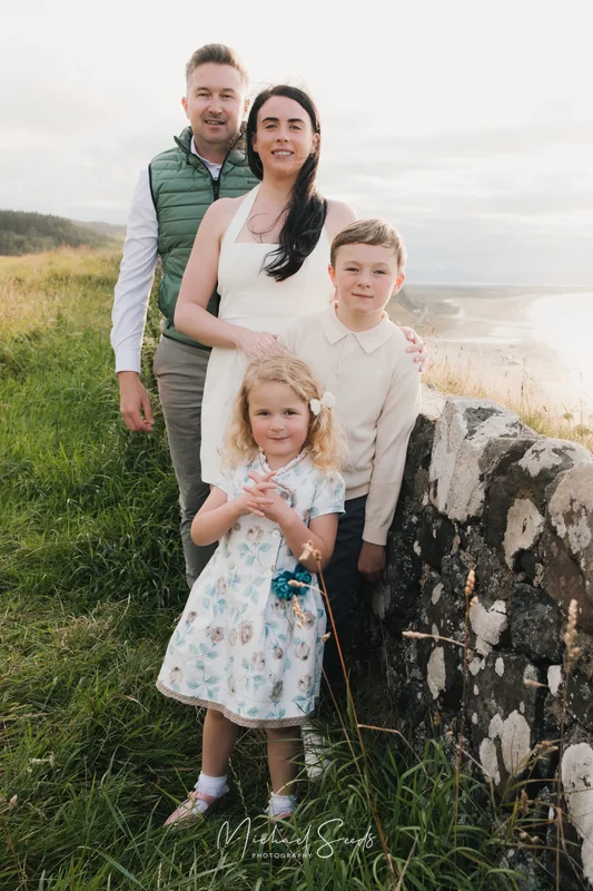 a couple poses with their children in front of a stone wall