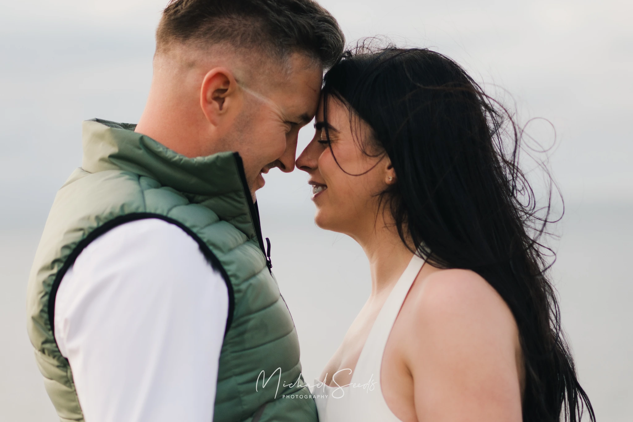 a bride and groom kiss on the beach during their engagement session