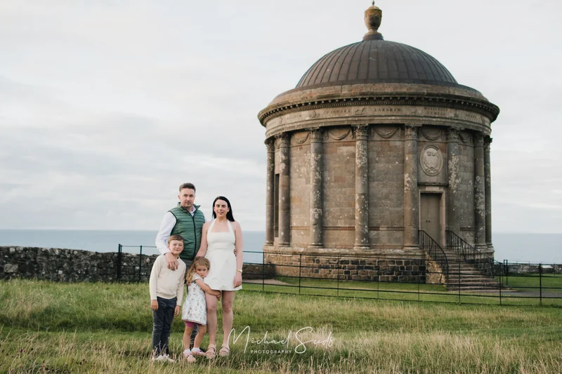 a family poses in front of a large stone building