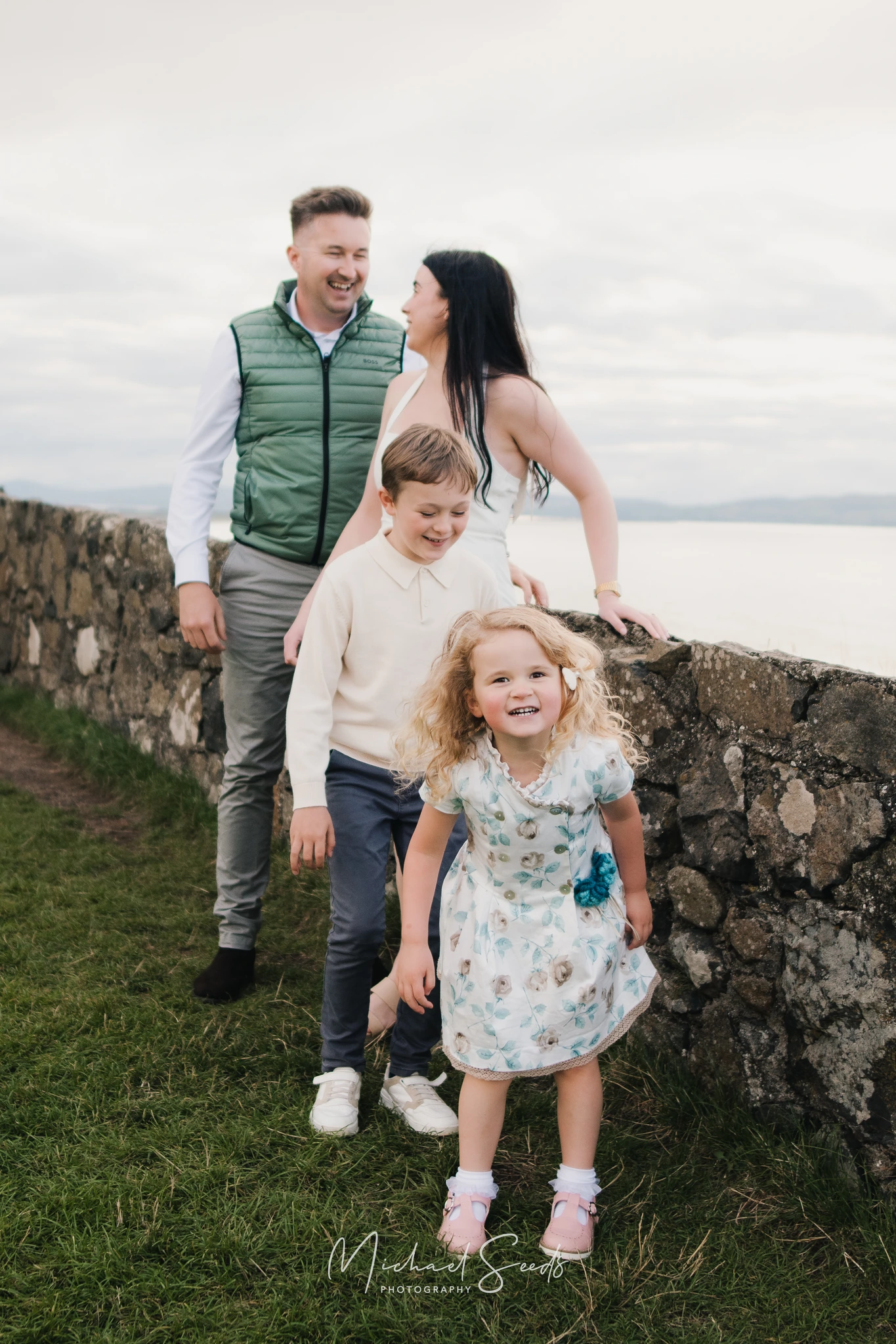 a family portrait of a couple and their children posing in front of the sea