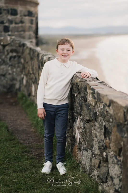 a young boy is standing on the edge of a stone wall