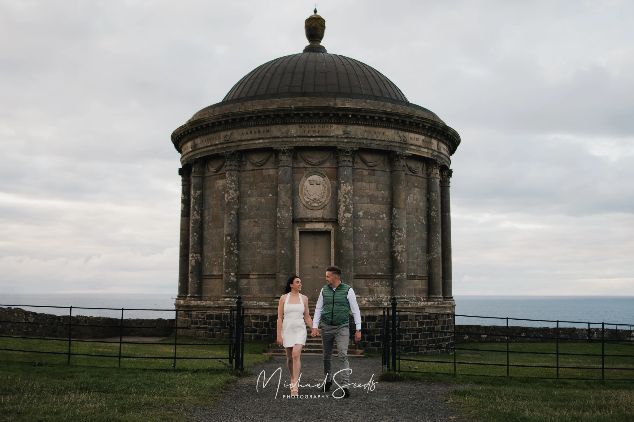 a bride and groom standing in front of a large stone building