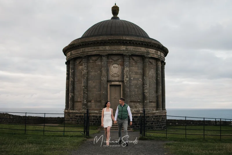 a bride and groom standing in front of a large stone building