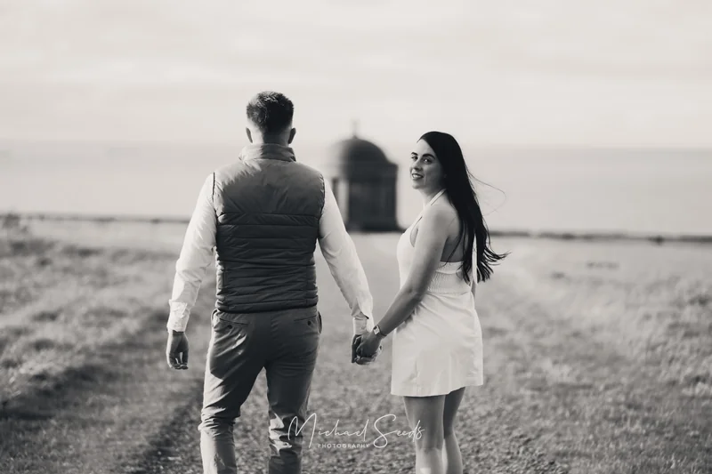 a man and woman walking down a path with a tree in the background