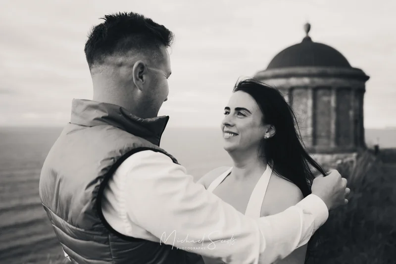 a bride and groom hugging in front of a castle