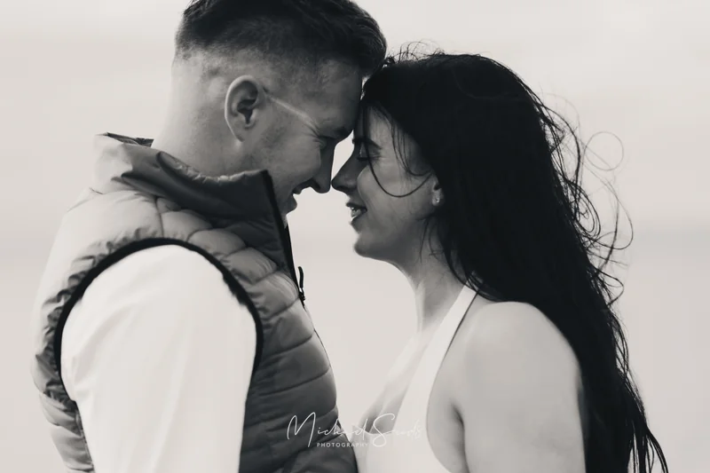 a man and woman hugging each other in front of a black and white photograph