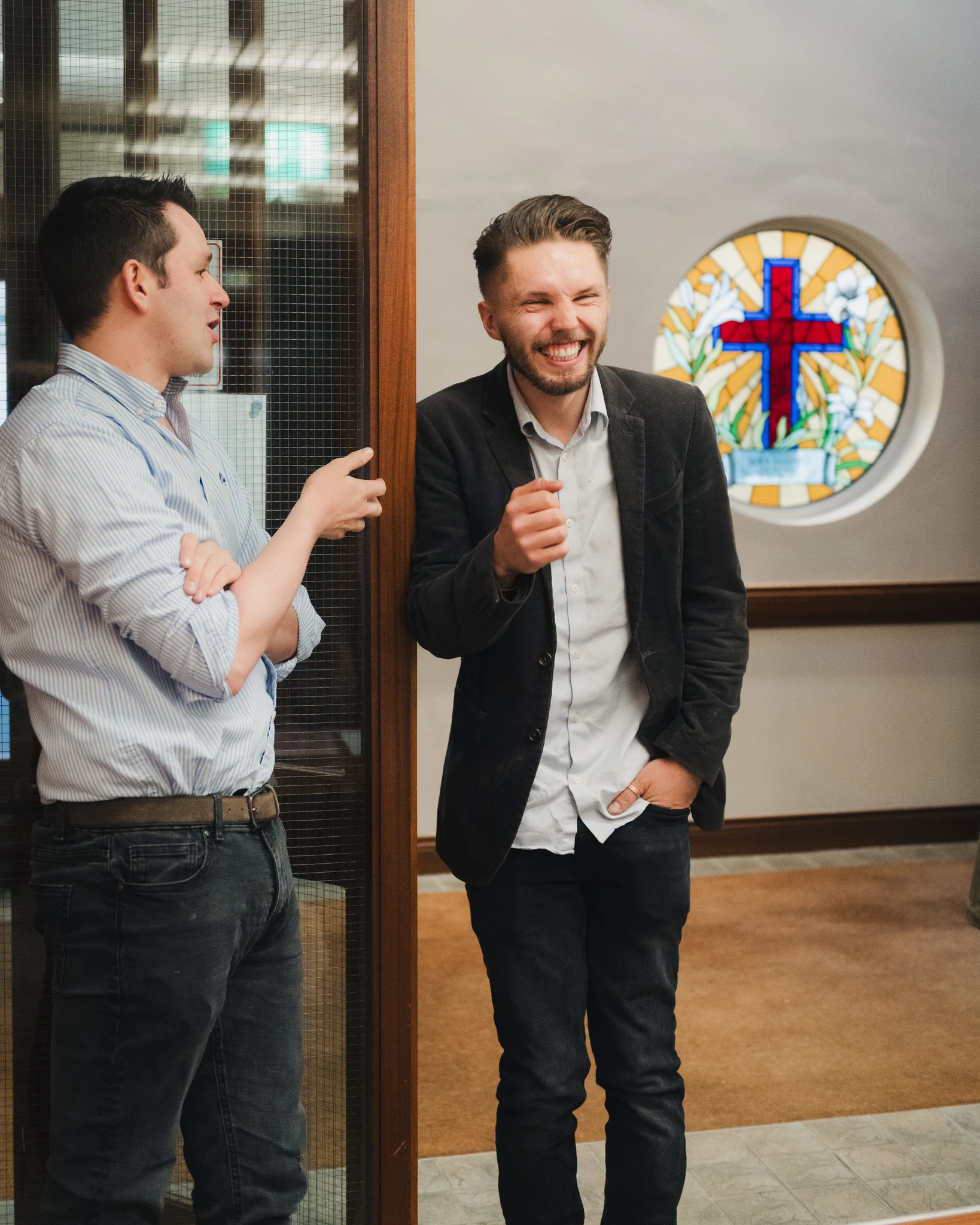 two men standing in front of a stained glass window