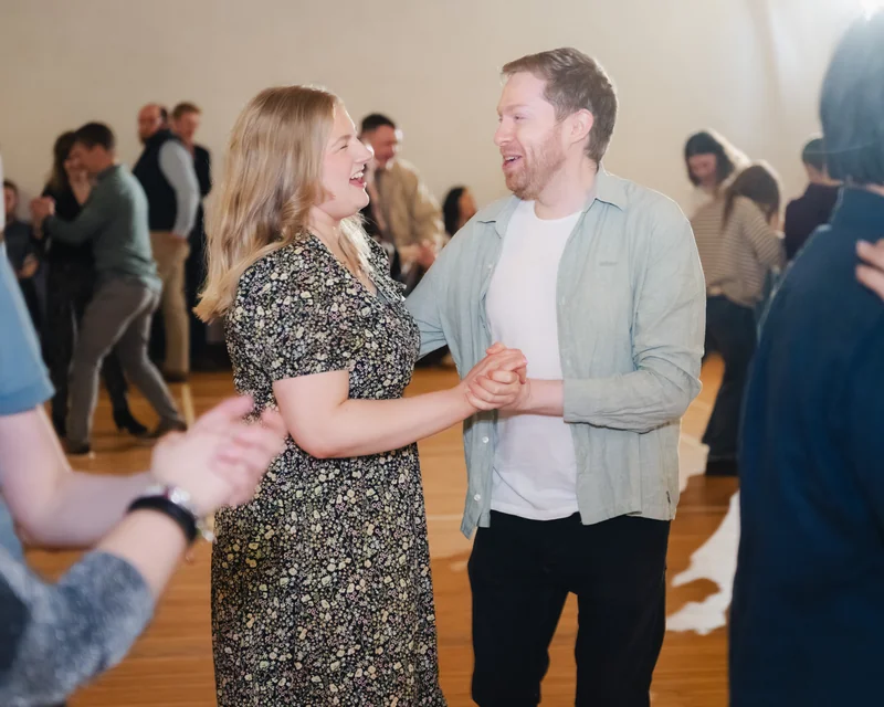 a man and woman dancing in a room full of people