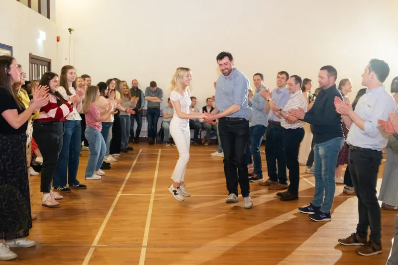 a man and woman dancing on a wooden floor in front of a crowd of people