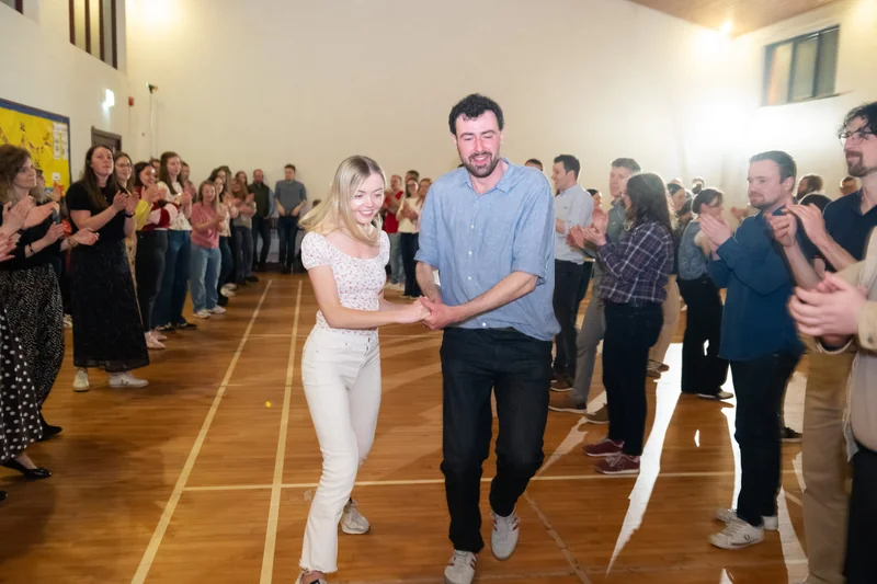 a man and woman dancing on a wooden floor in front of a crowd of people