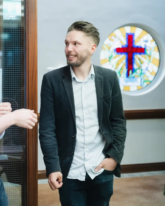 two men standing in front of a stained glass window