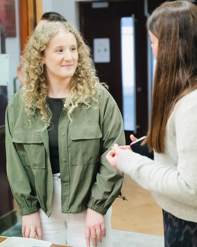 a young woman is talking to another young woman in a room