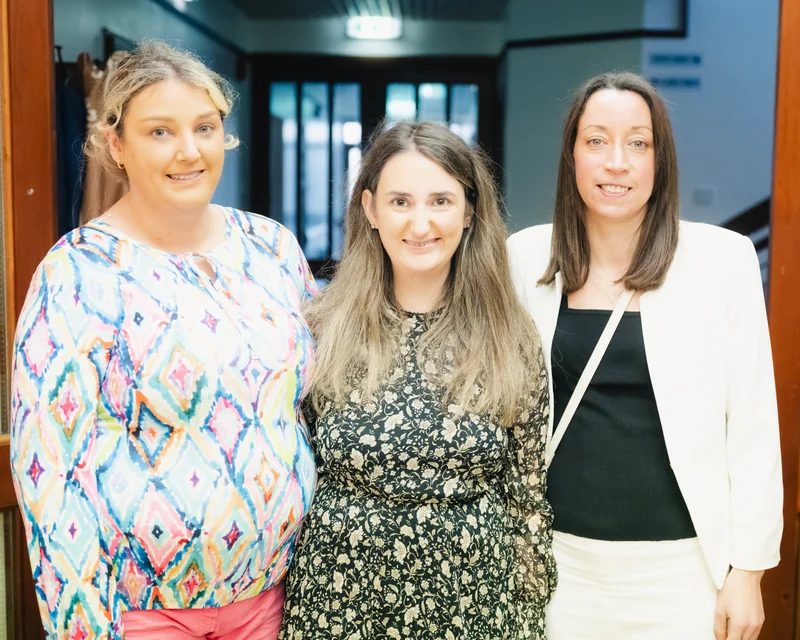 three women standing next to each other in front of a doorway
